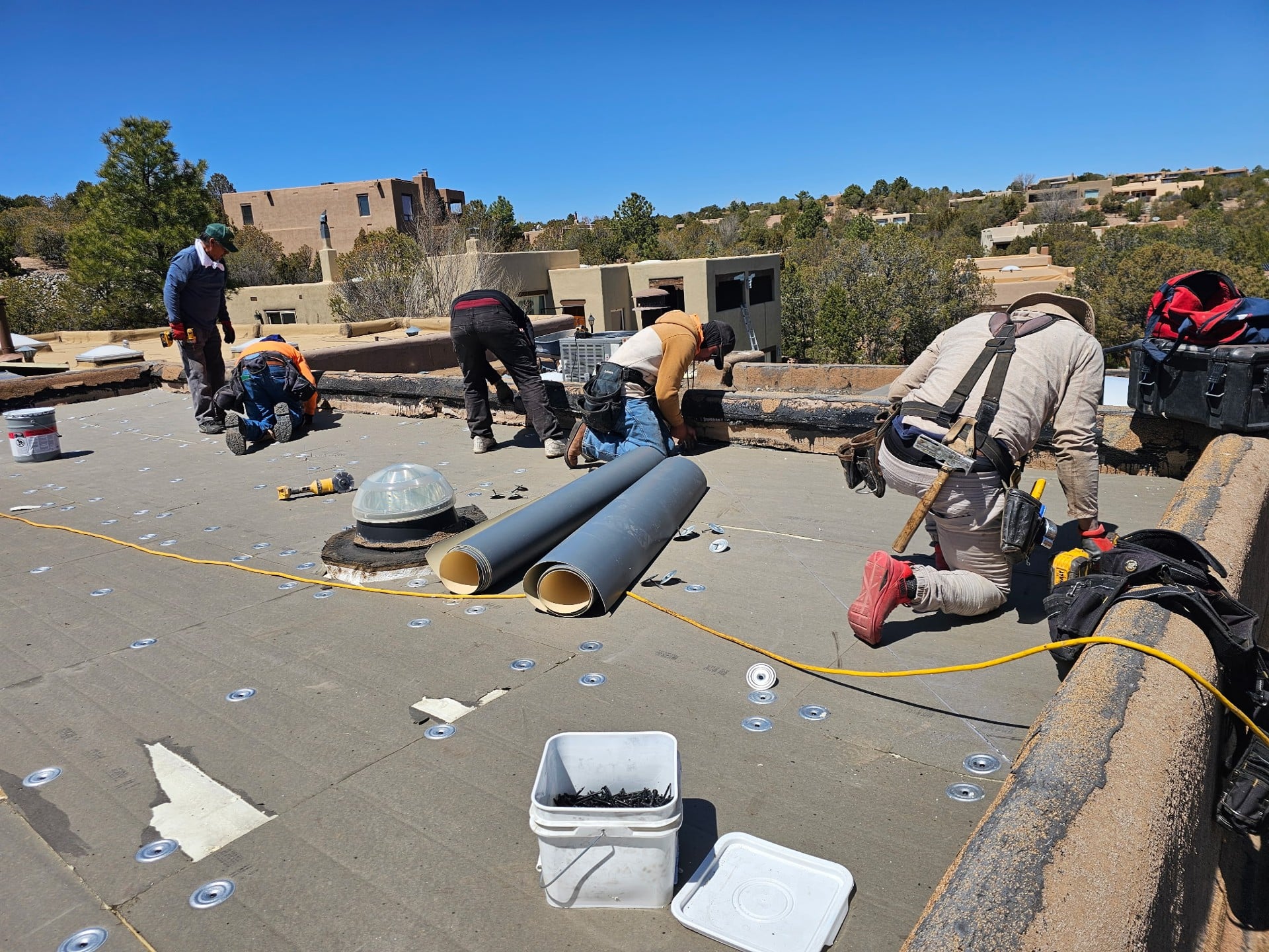 Roofing crew preparing material on a flat roof