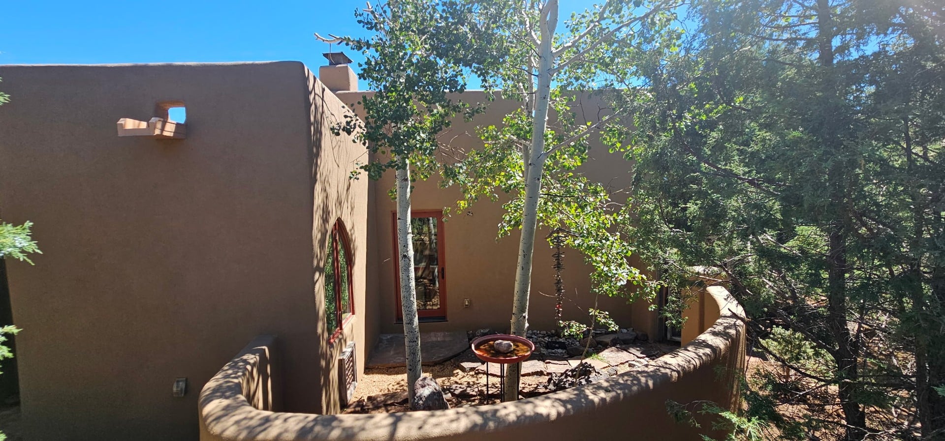 Warm stucco exterior with trees and a stone garden wall